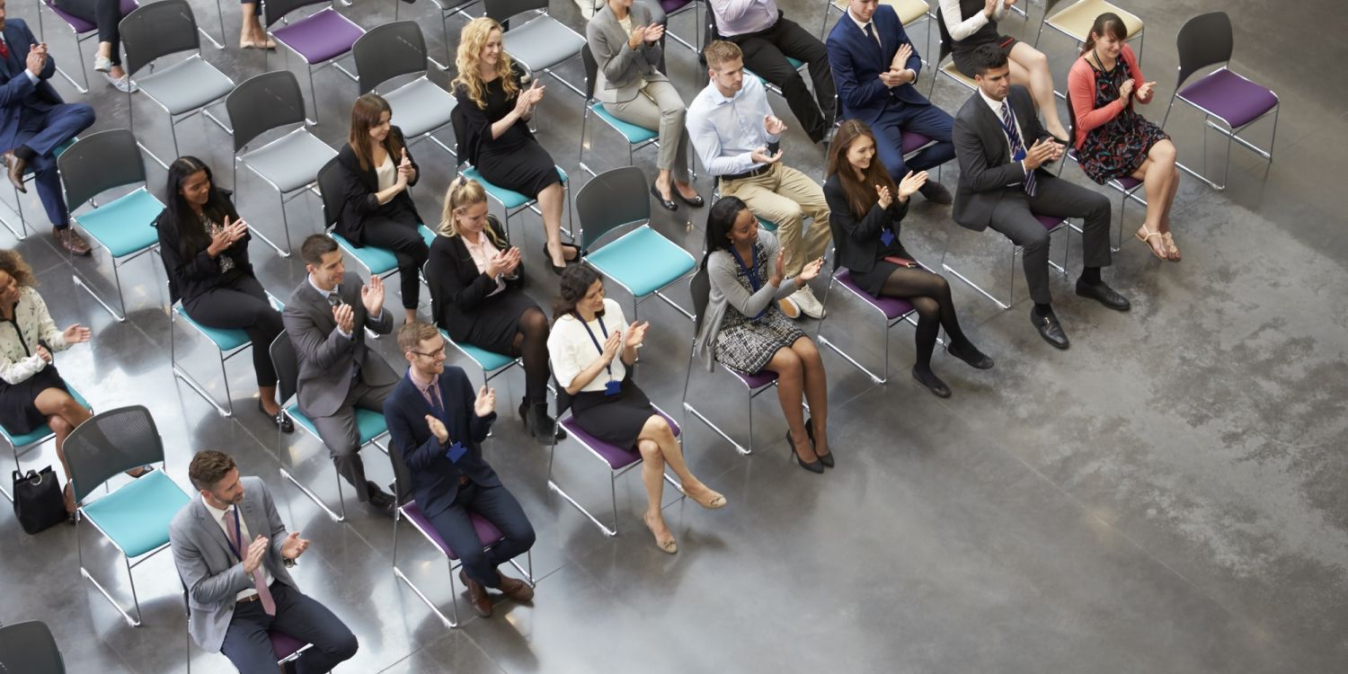 Overhead View Of Audience Applauding Speaker At Conference